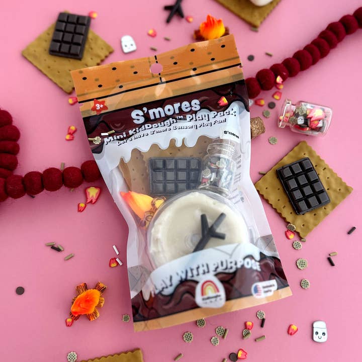 S'mores-themed play food set with packaging on a pink background