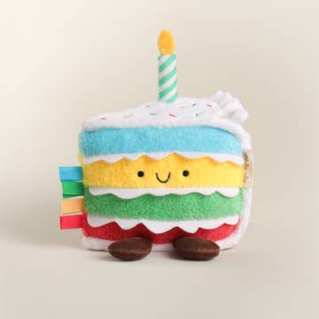 Plush toy cake with a candle on a beige background