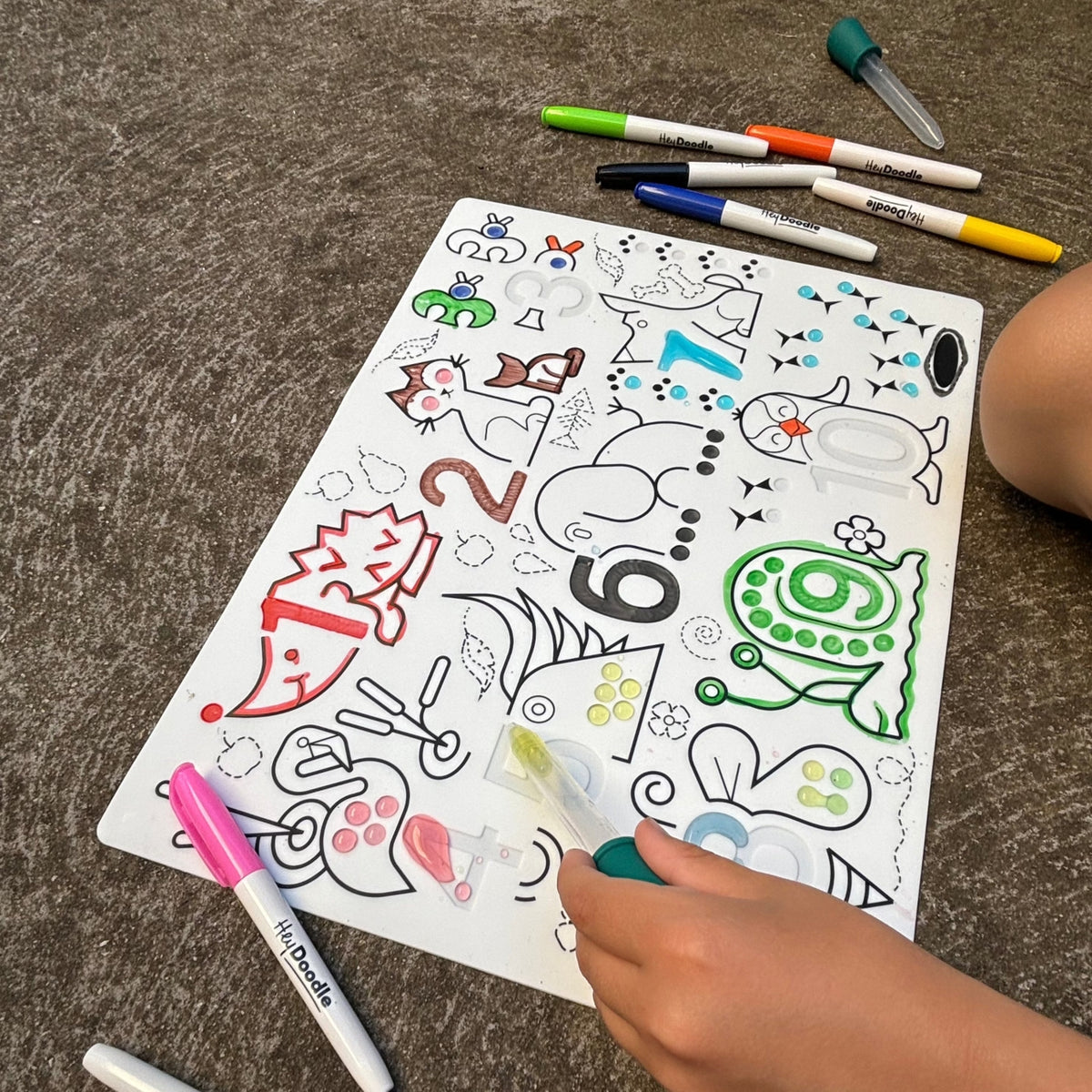 Coloring book with various designs on a surface with markers around