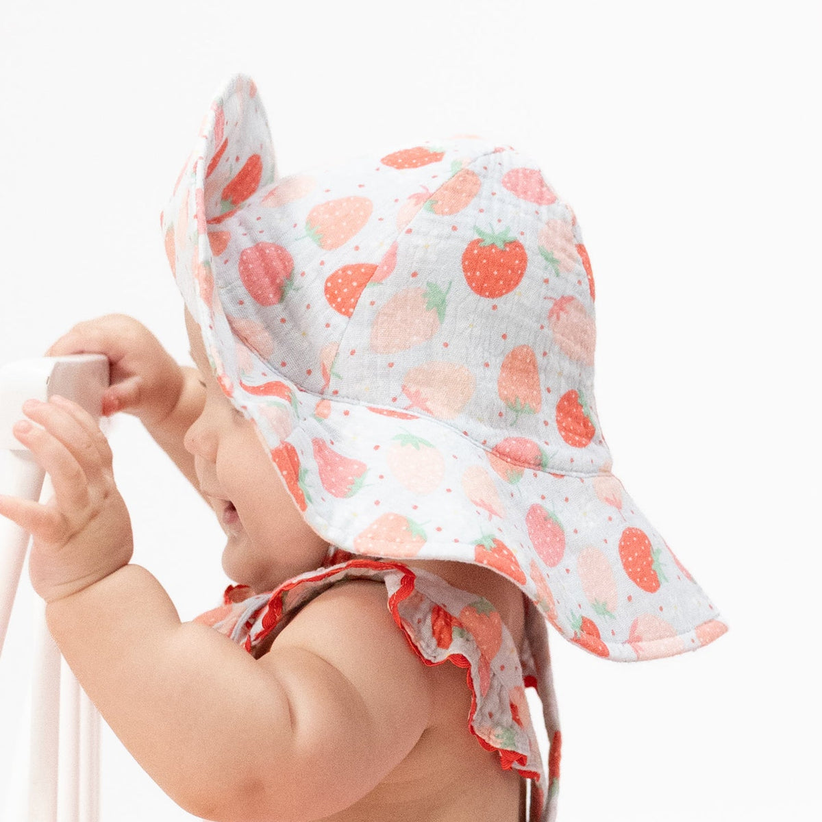 A Baby wearing baby sun hat with strawberry pattern on a white background