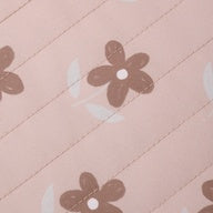 A close-up of a light pink fabric with a repeating pattern of brown flowers and white crescent shapes.
