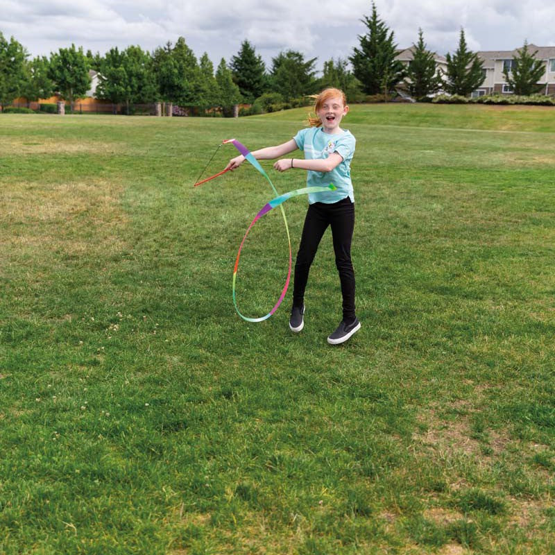 Girl playing with a colorful hula hoop in a grassy field