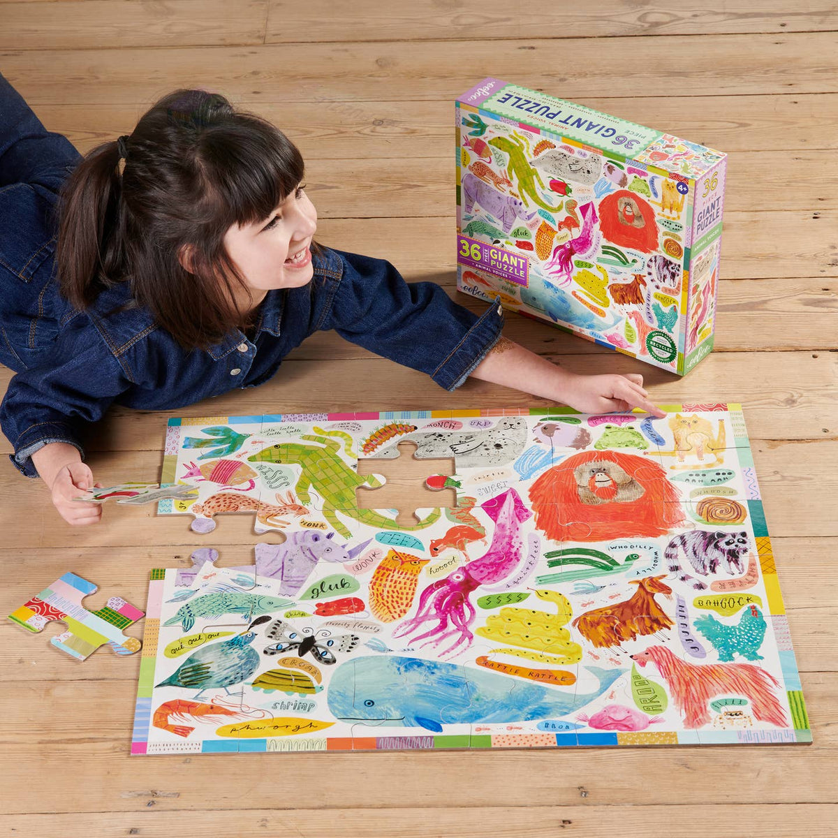 Child playing with a colorful puzzle on a wooden floor next to the puzzle box.