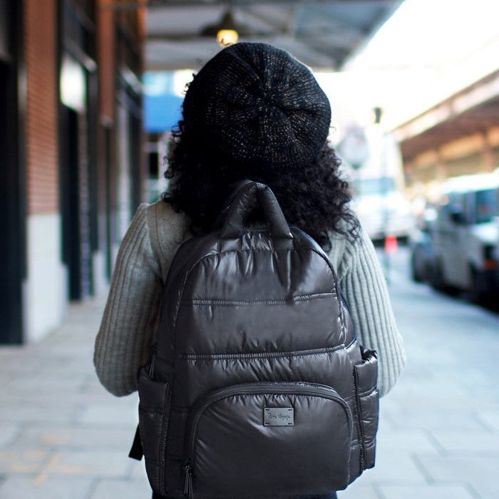 Person wearing a black backpack walking on a city street