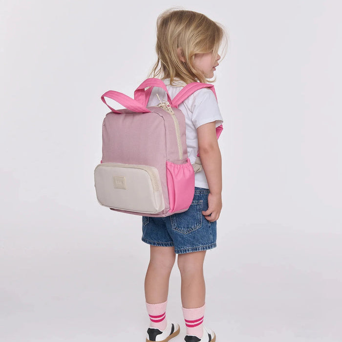Child wearing a pink and beige backpack on a white background