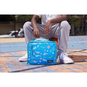 Person sitting on a bench with a blue floral-patterned bag