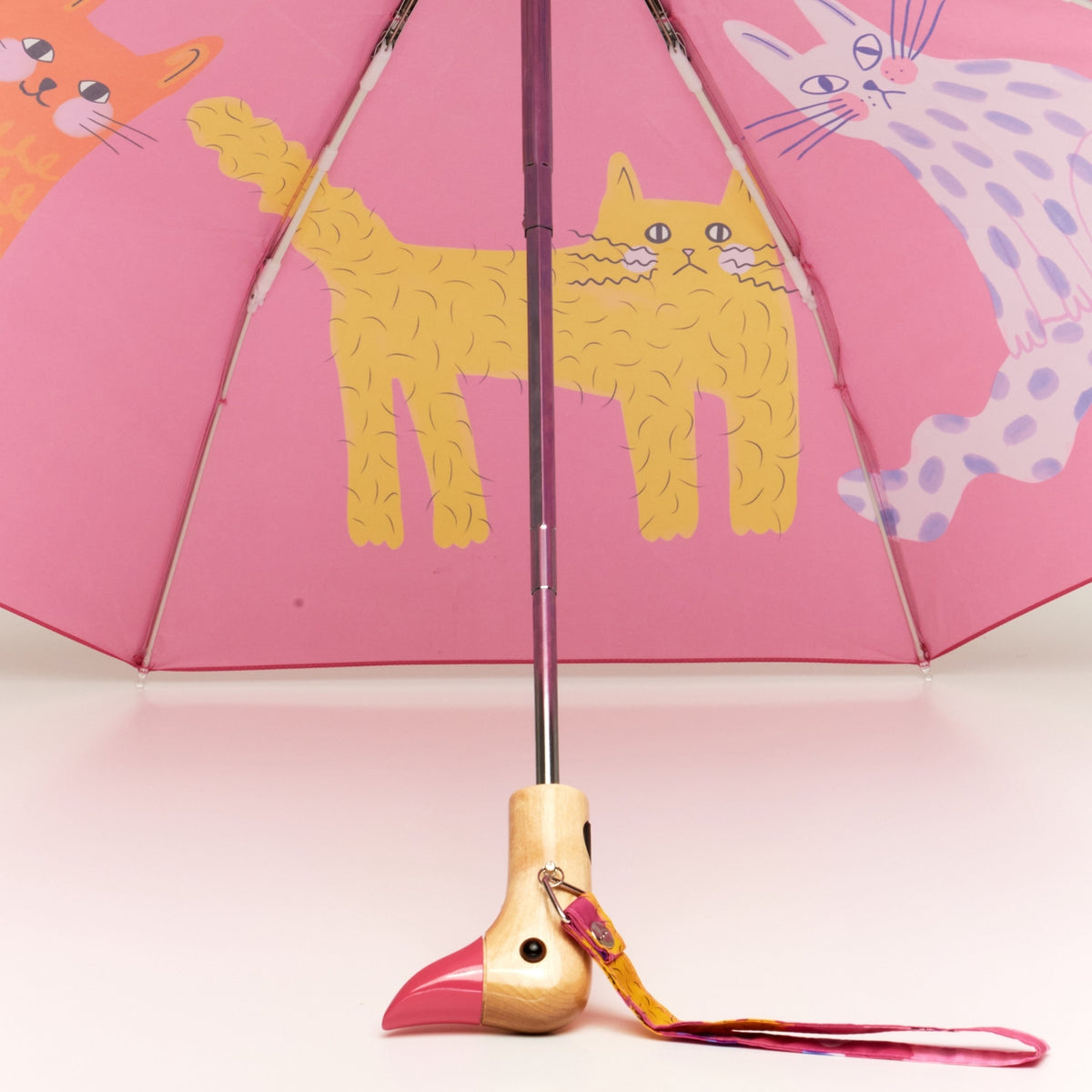 Pink umbrella with cat illustrations on a pink background