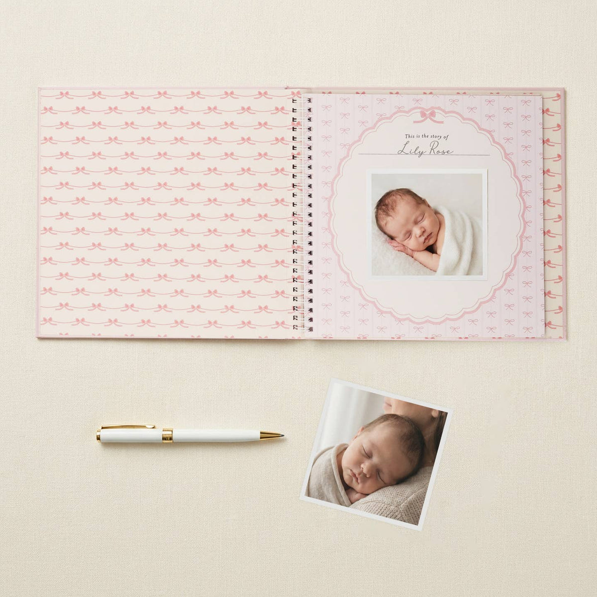 Open baby memory book with photos and a pen on a light background