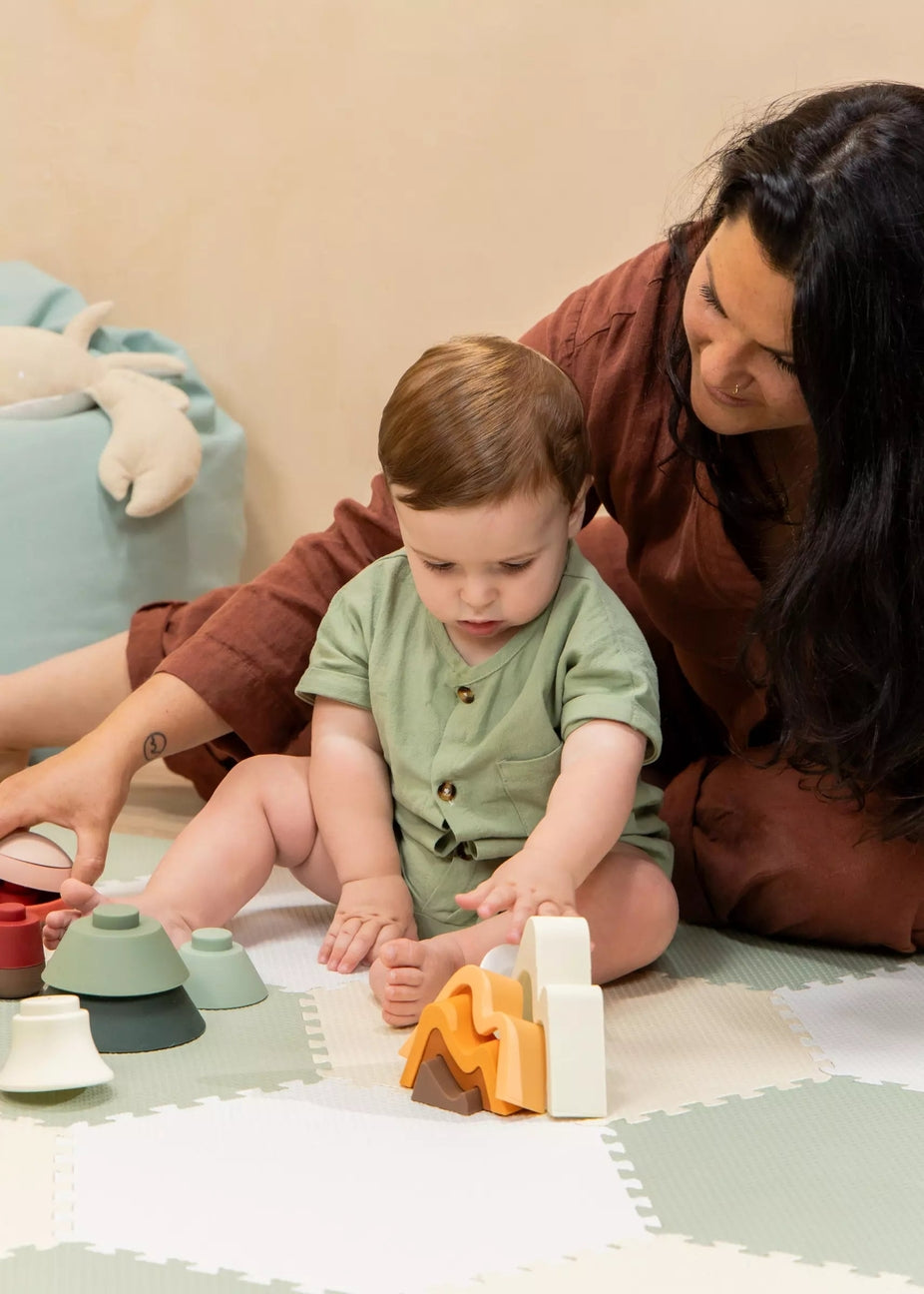 Woman and child playing with toys on a mat