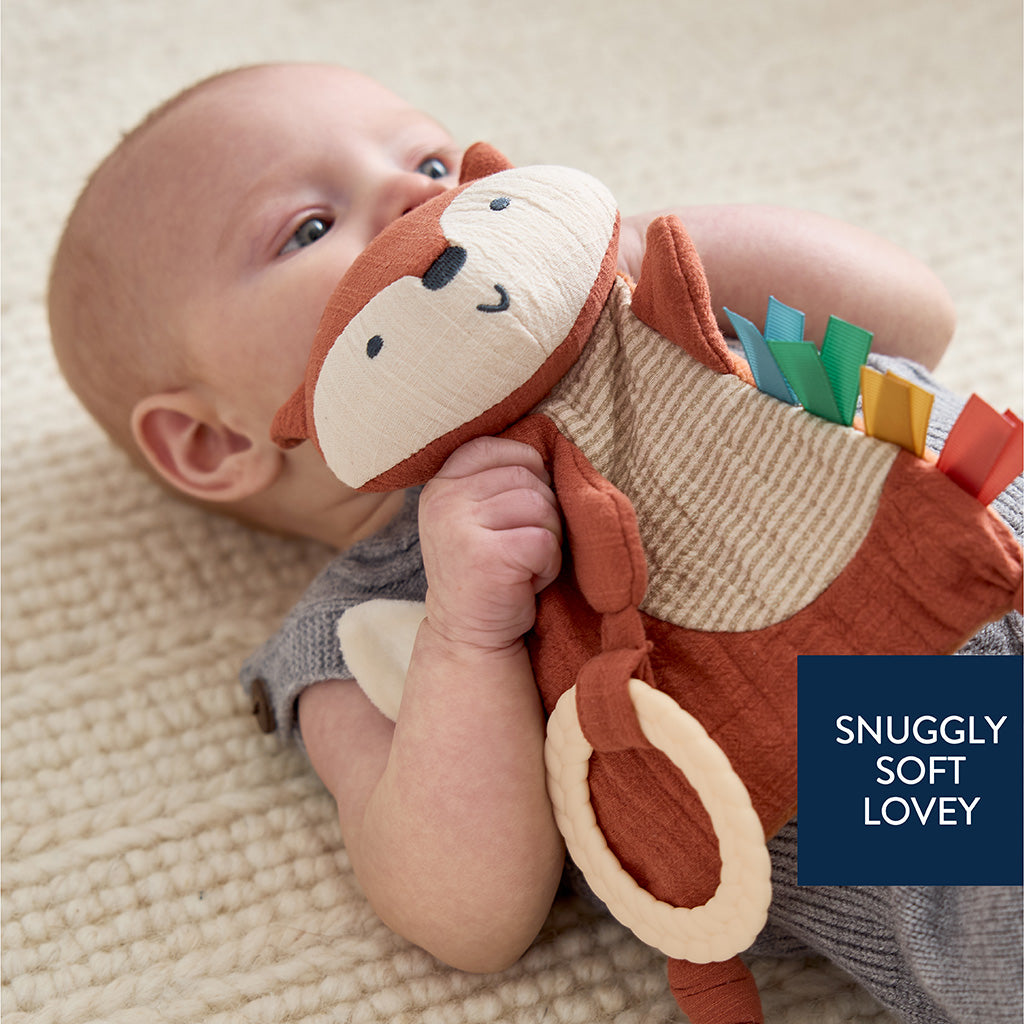 Baby holding a soft toy with text 'Snuggly Soft Lovey' on a neutral background