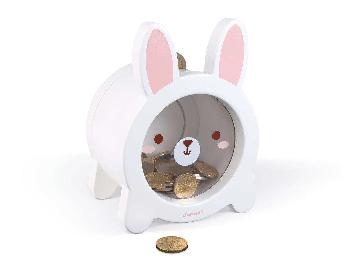 A white rabbit-shaped coin jar with pink inner ears and a cartoon face, shown on a clean white background with coins inside and one coin in front.