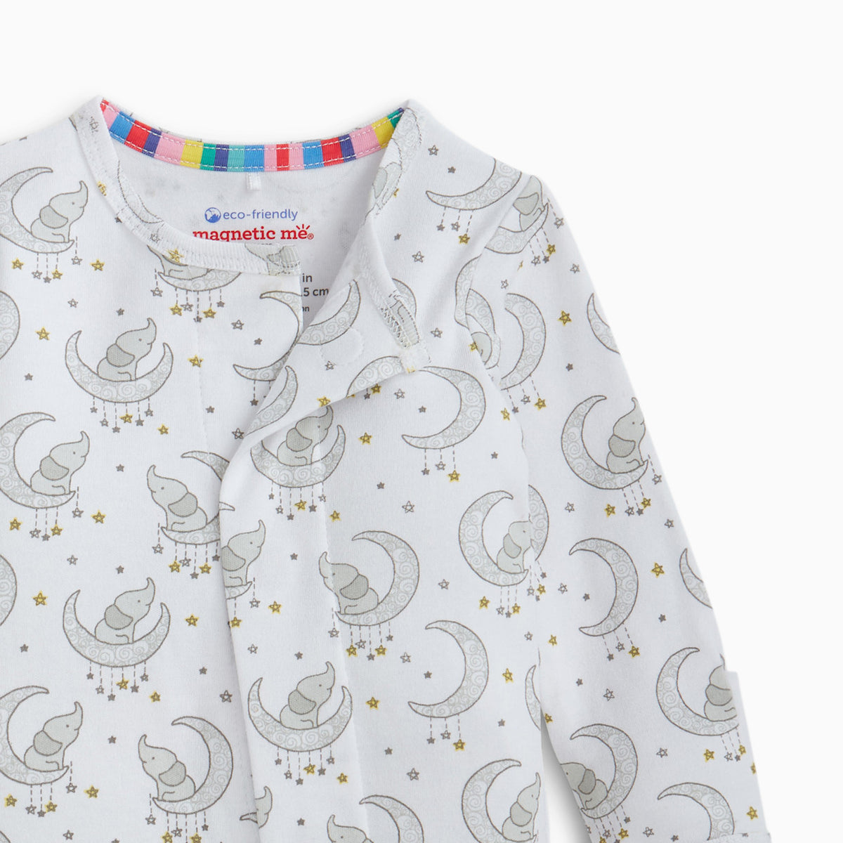 A close-up of a baby long-sleeve sleep suit or pajama top with an all-over print of gray crescent moons, owls, and small gold stars on a white background. The inside collar shows the 'eco-friendly magnetic me' brand label.