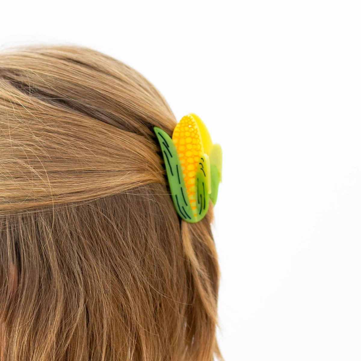 Corn-shaped hair clip on a person's hair against a white background