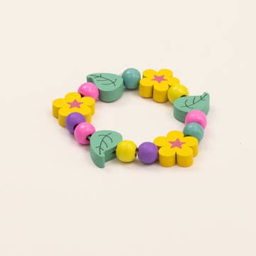 Colorful wooden bracelet with flower and leaf shapes on a beige background