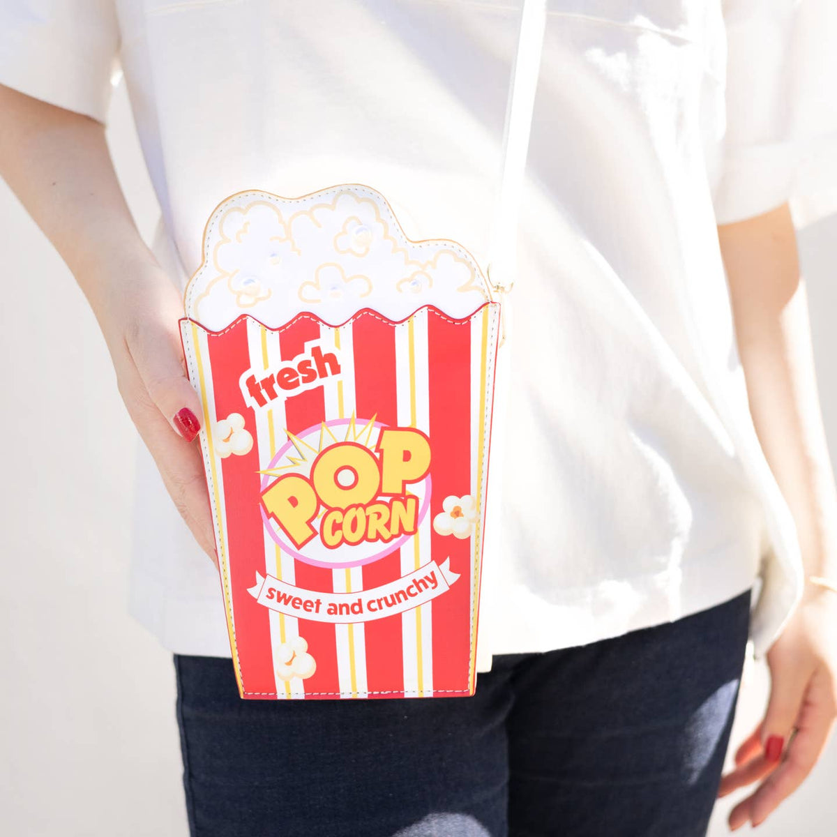Person holding a popcorn-themed pouch with a white background