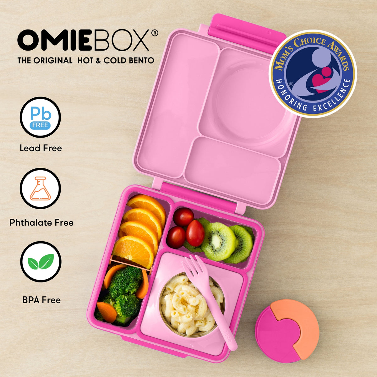 Pink bento box with compartments filled with food on a beige background, featuring OmieBox branding and certification logos.