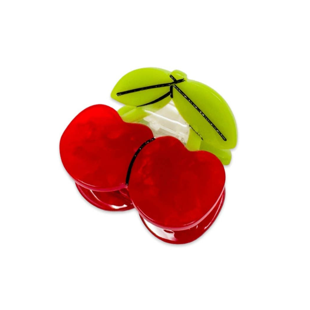 Two red plastic cherries with a green leaf on a white background