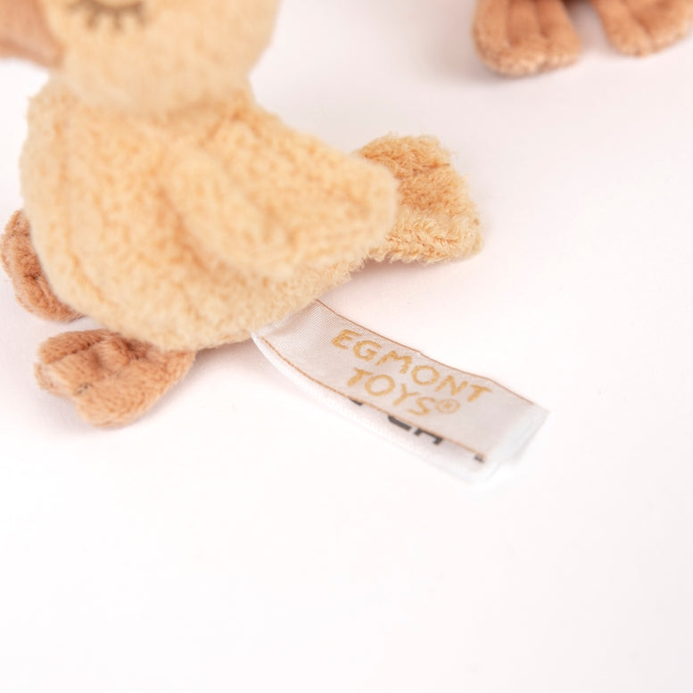 Close-up of a small plush toy in light tan fabric with a visible tag reading EGMONT TOYS, photographed on a clean white background.