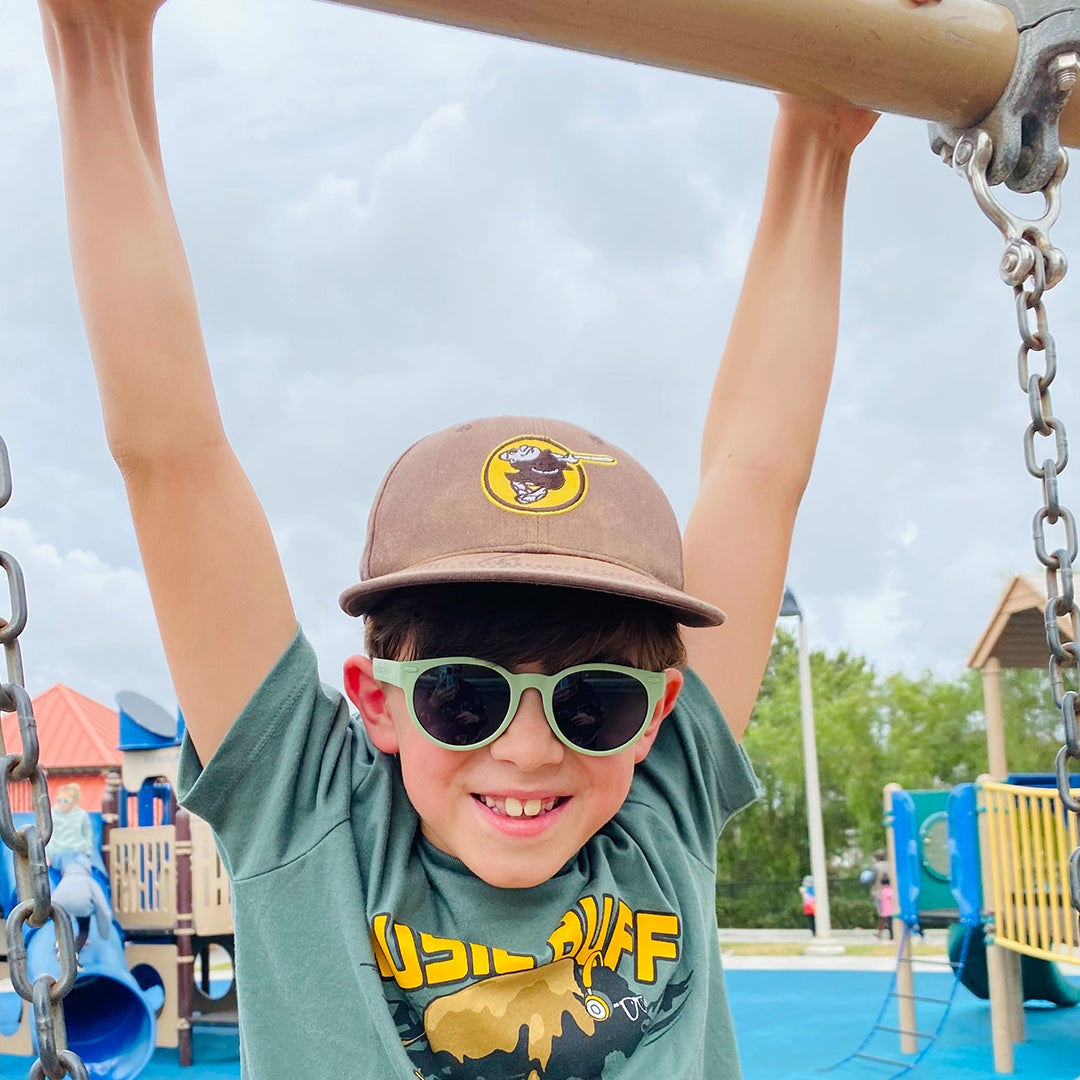 Child wearing sunglasses and a cap on a playground