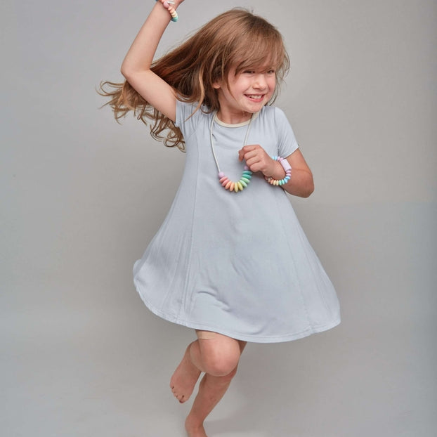 Young girl in a light blue dress jumping on a plain background