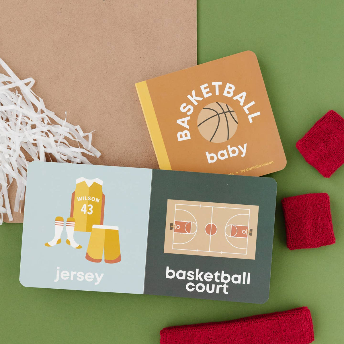 Two children's books on a green surface with basketball-themed illustrations and text.