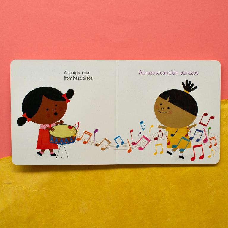 Illustrated book page with two children playing drums and musical notes on a pink and yellow background