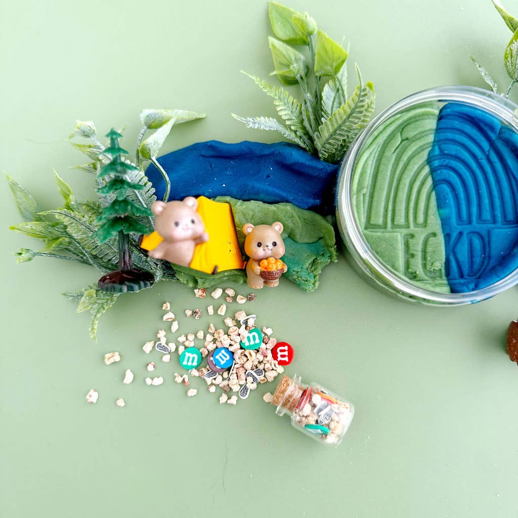 Miniature camping scene with two bear figurines, a tent, and a jar labeled 'ECO' on a green background.