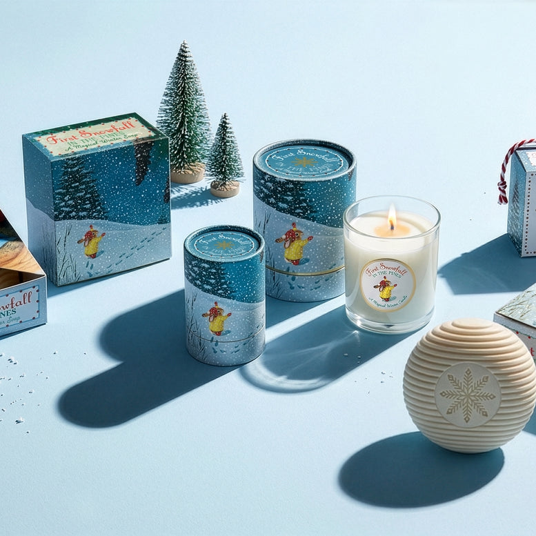 Collection of candles and packaging on a light blue background with decorative trees.