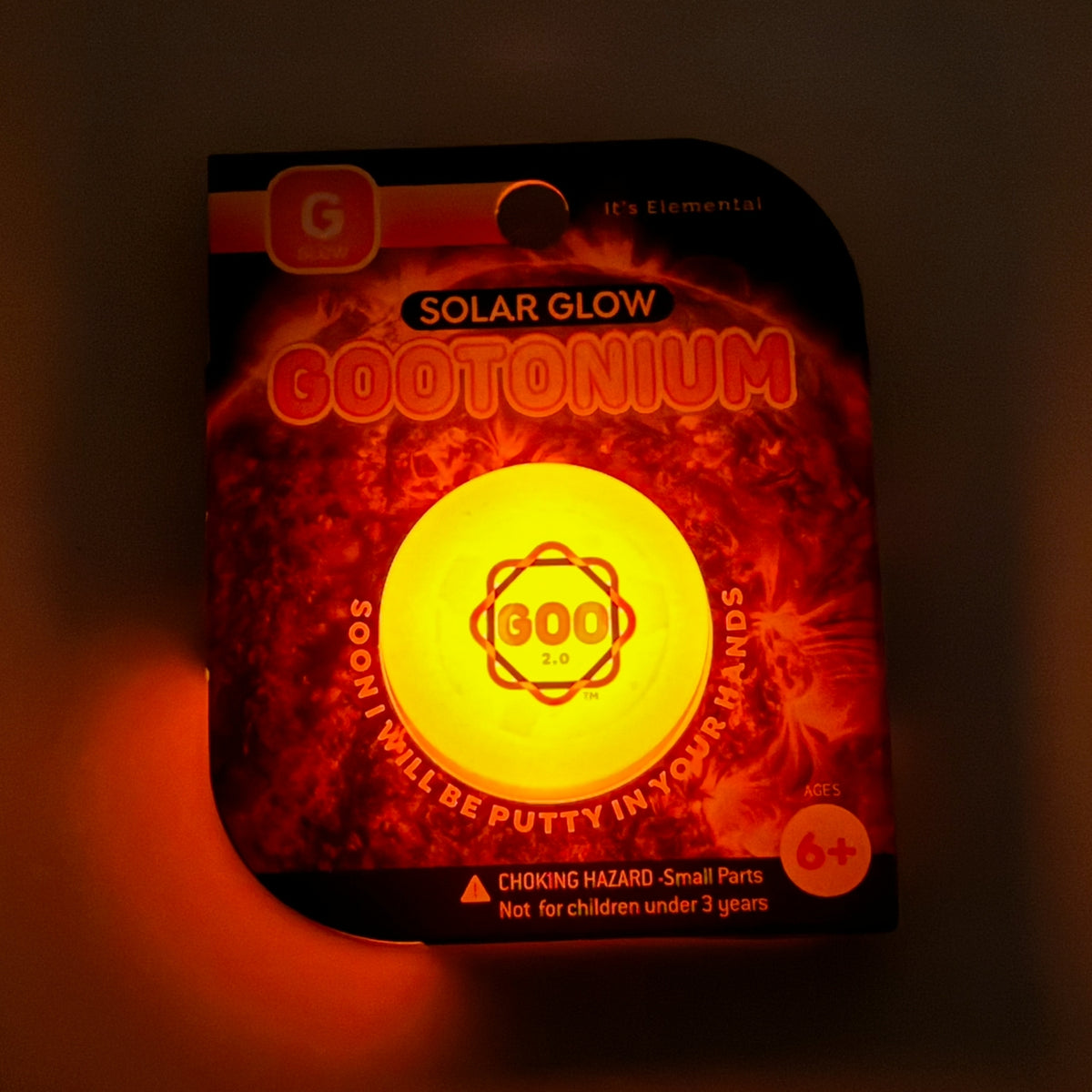 Packaged solar glow product with glowing yellow center on a dark background