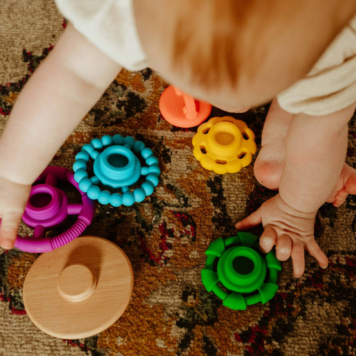 Child playing with colorful toys on a patterned carpet