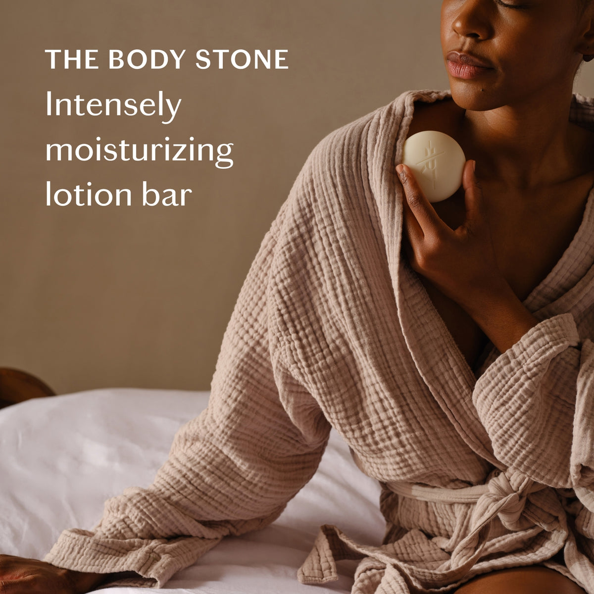 Woman in a robe holding a lotion bar with text about 'The Body Stone' lotion bar.