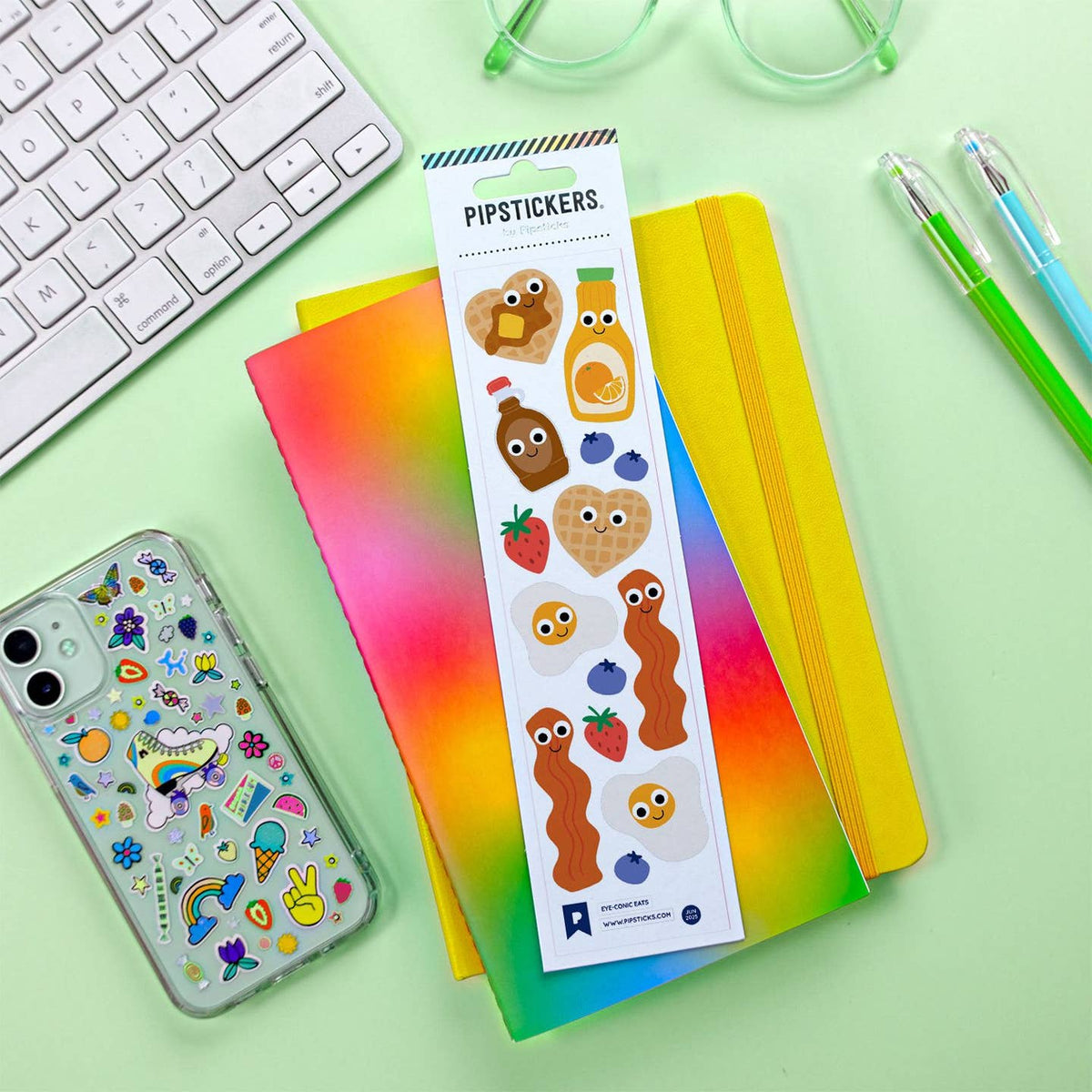 Pipstickers packaging with colorful designs on a green surface with stationery items.