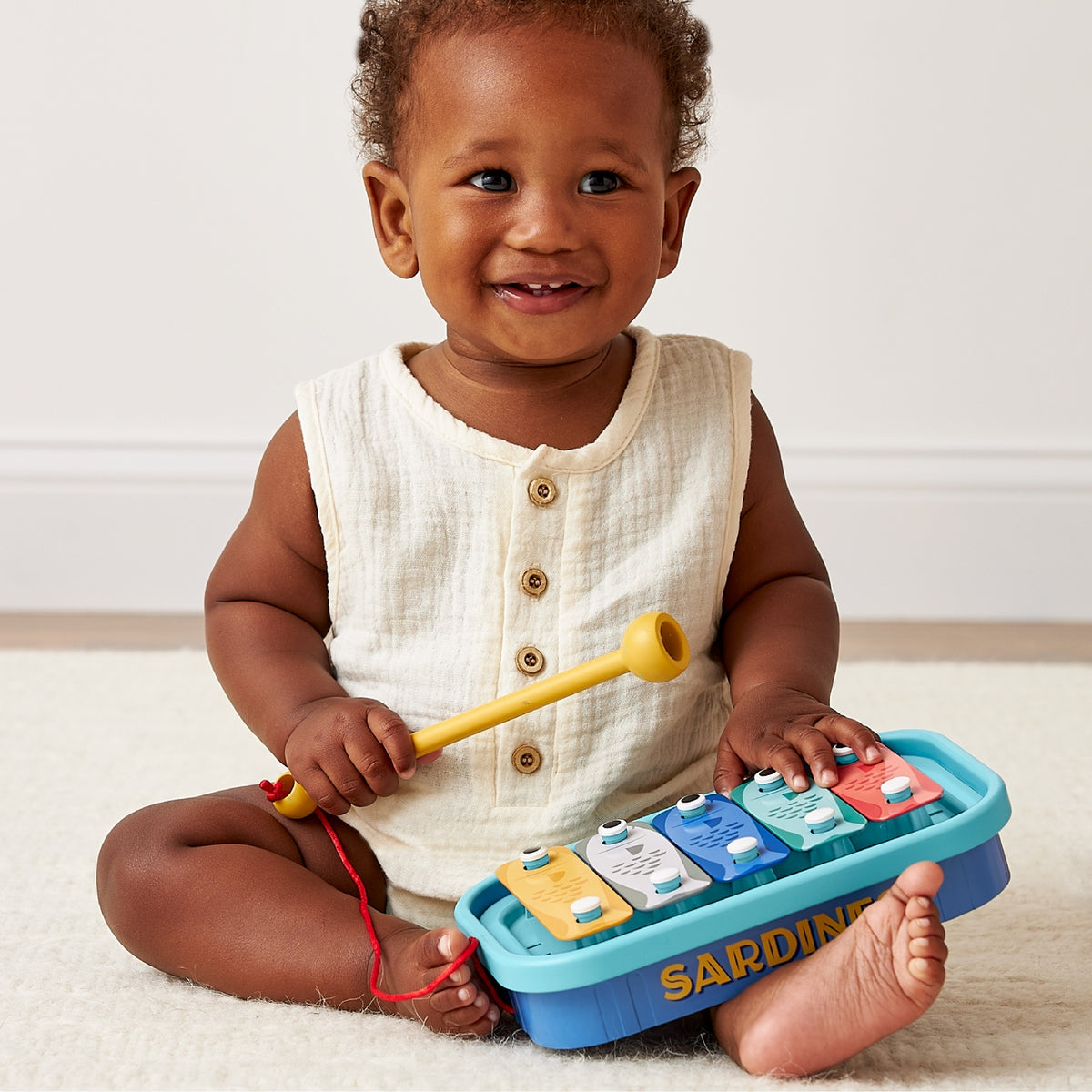 Child playing with a colorful toy piano on a light-colored floor.