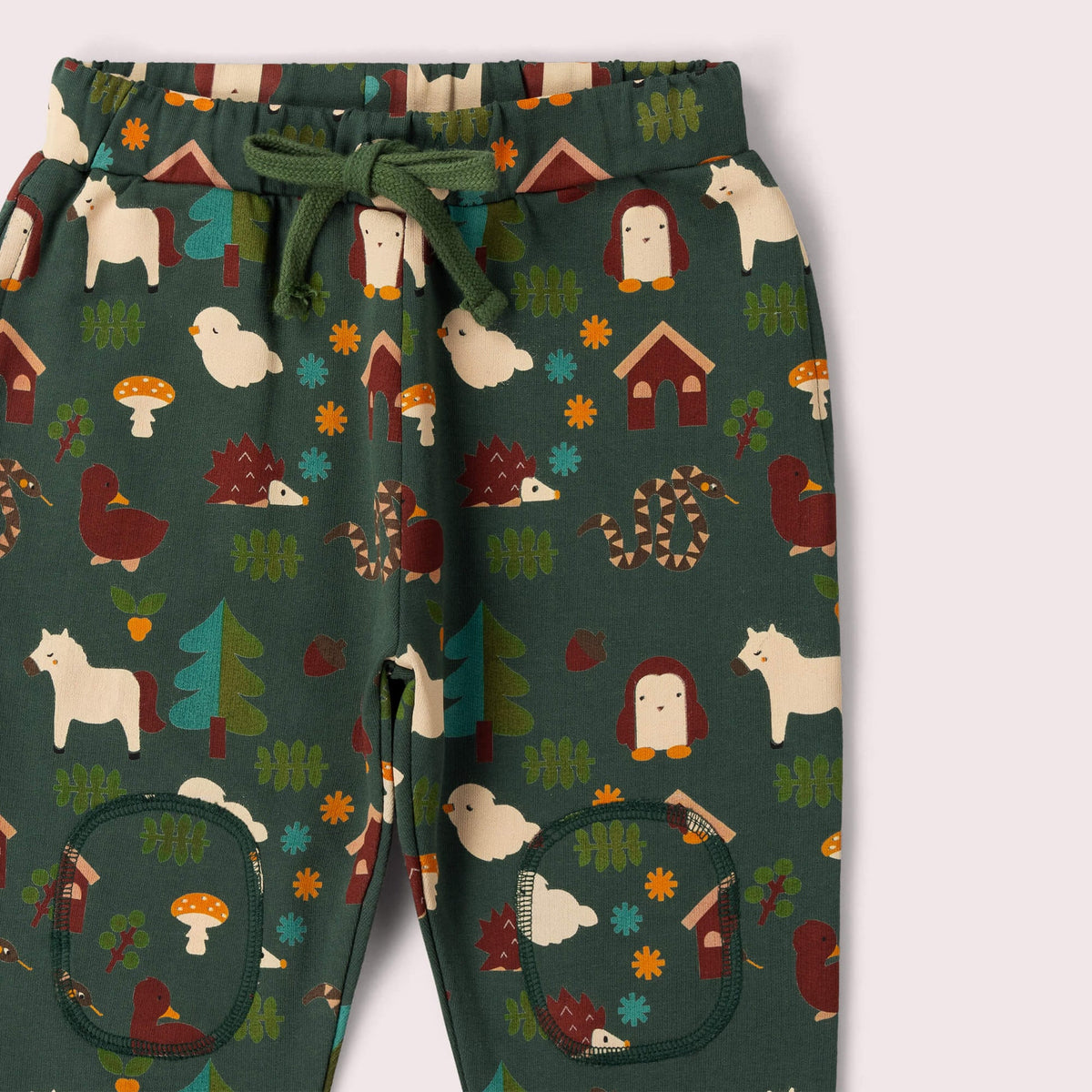 A pants with a forest-themed print on a dark green background, featuring woodland motifs like trees, mushrooms, houses, and animals matching green drawstring.