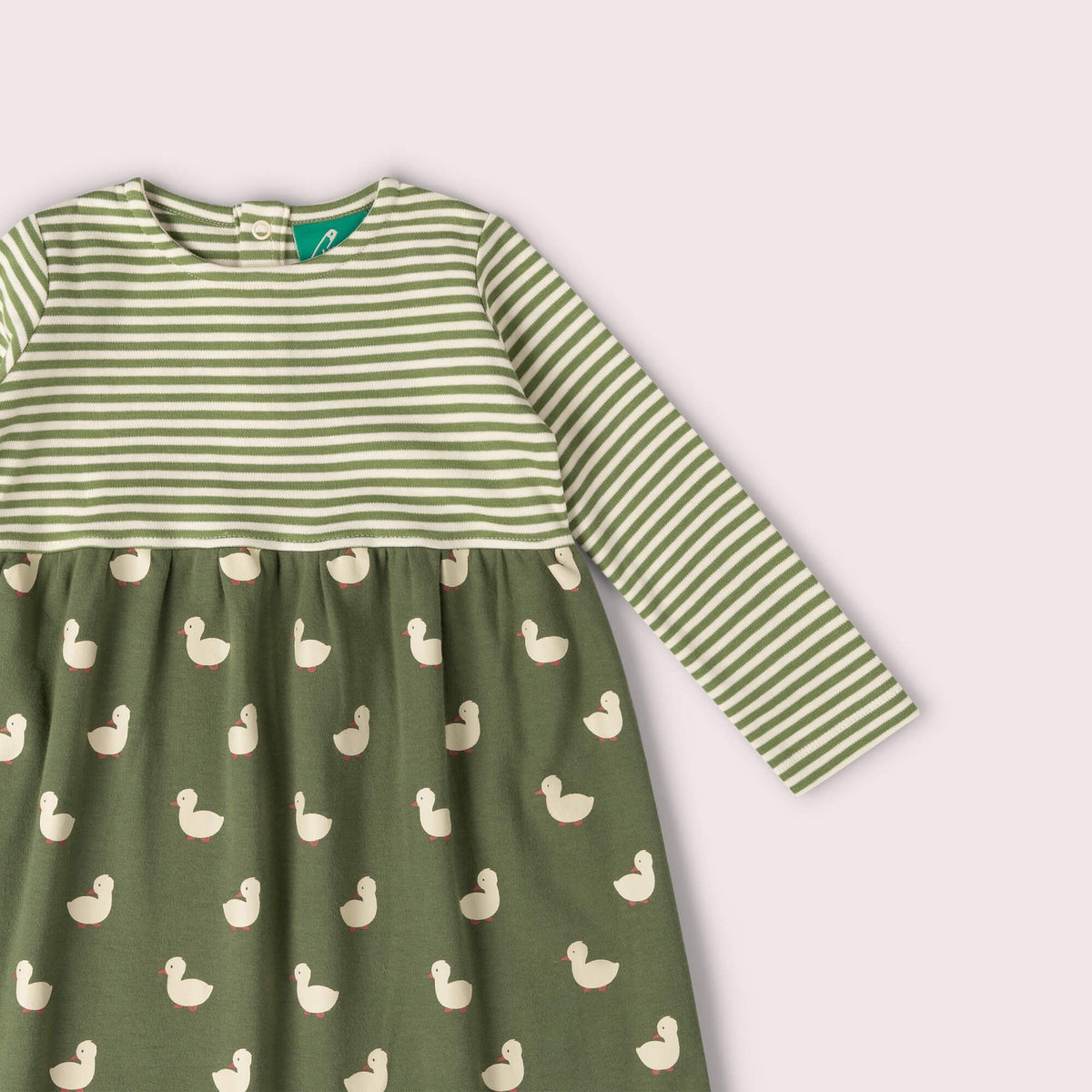 A long-sleeve baby dress in sage green, featuring a striped bodice and sleeves with a white duck print skirt, shown against a pale pink background.