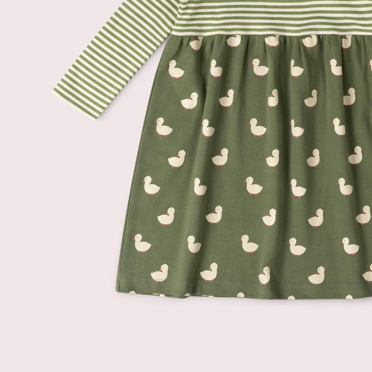 A long-sleeve baby dress in sage green, featuring a striped bodice and sleeves with a white duck print skirt, shown against a pale pink background.