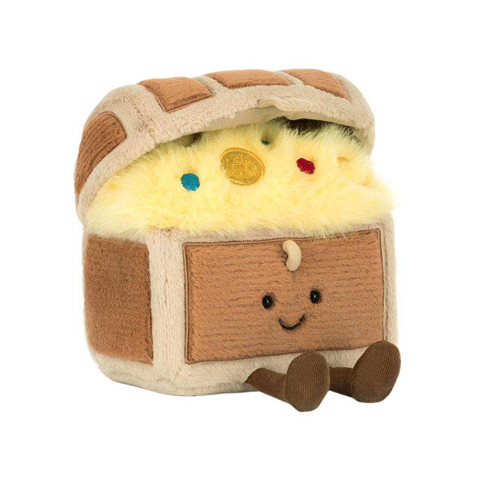 A plush toy shaped like a treasure chest with a smiling face, featuring yellow faux fur inside, brown and beige fabric textures, and small colorful gem accents on a plain white background.
