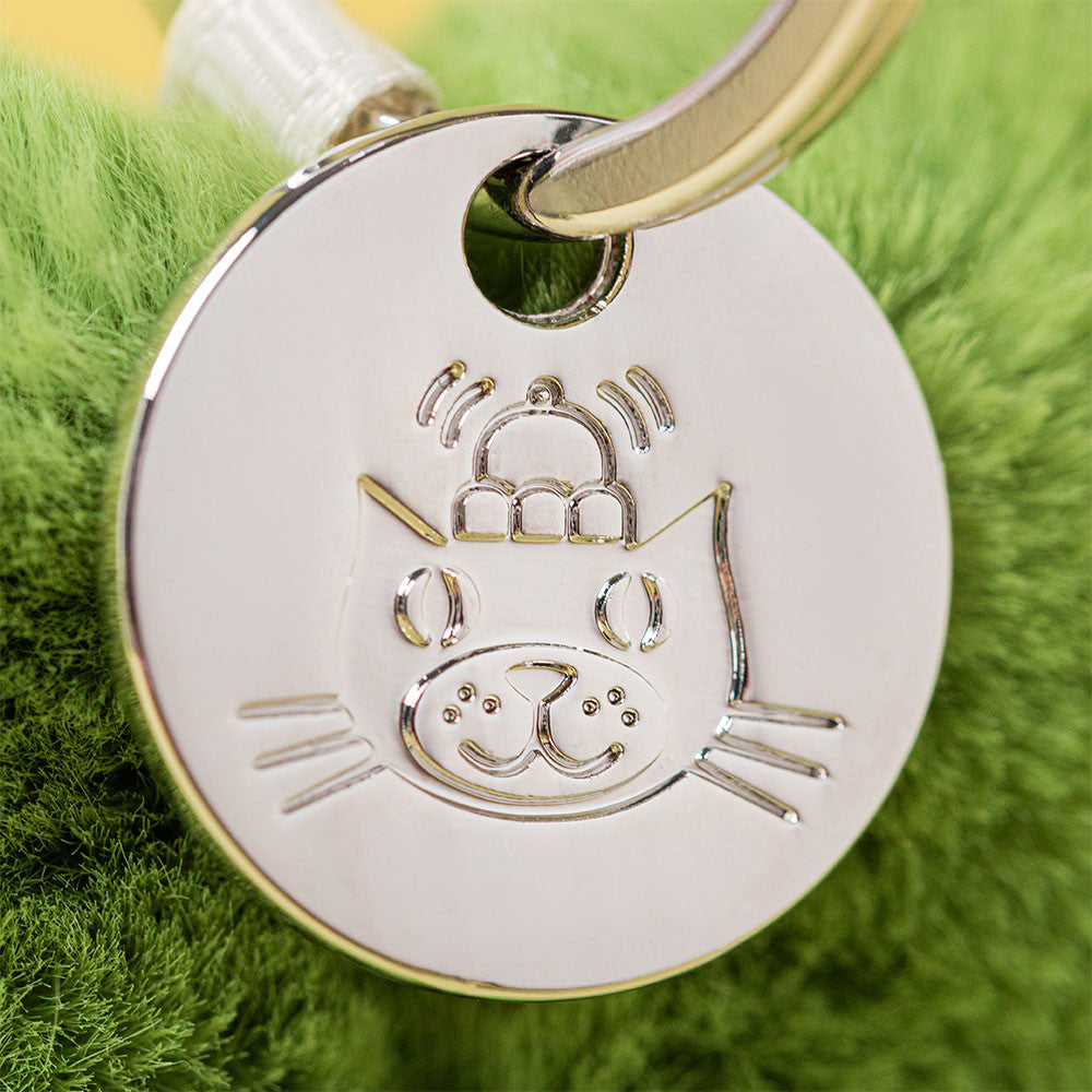 Silver cat-shaped keychain tag on a green textured background