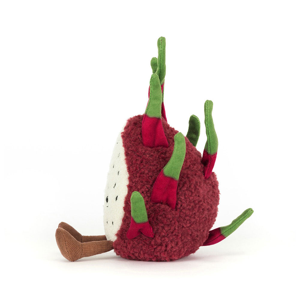 A plush toy resembling a dragon fruit with fuchsia fur and green fronds, smiling and sitting upright.