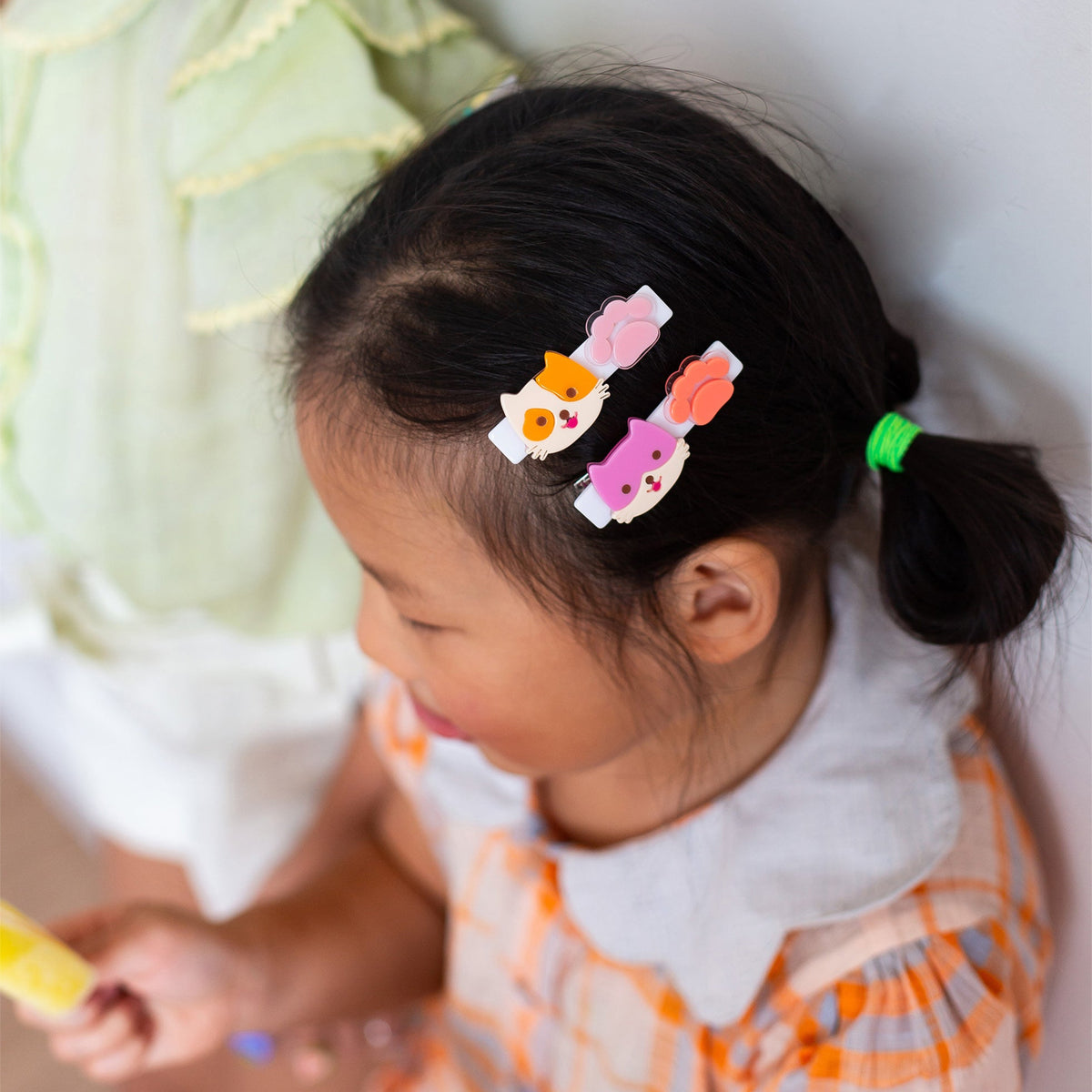 Child with colorful hair clips in a ponytail, sitting next to an adult.