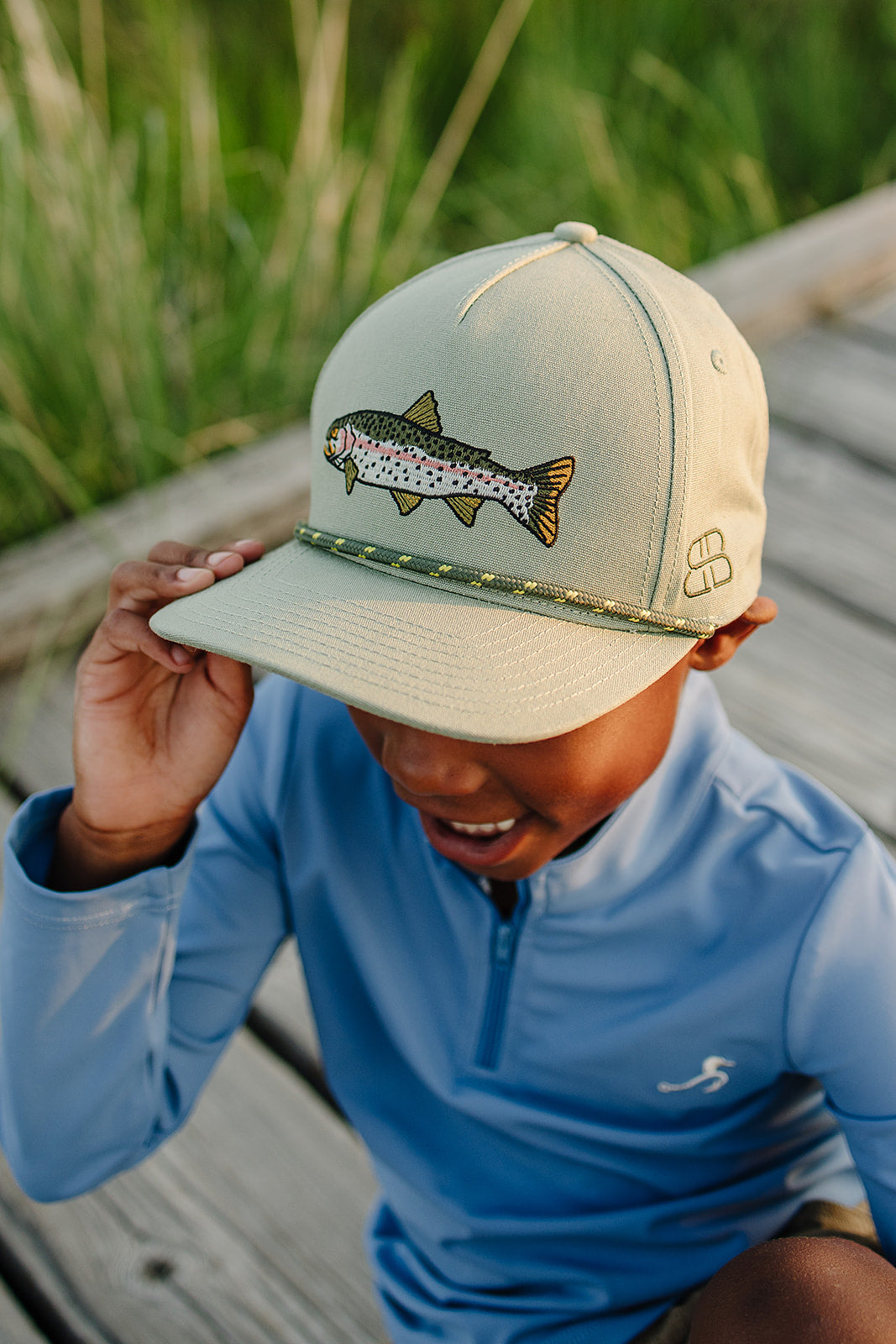 Person wearing a beige cap with a fish design outdoors