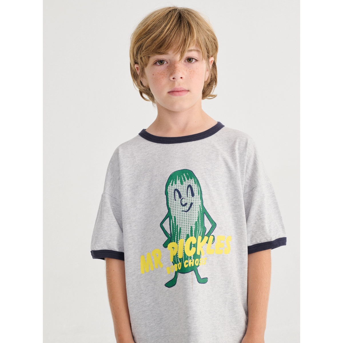 Child wearing a gray t-shirt with a pickle character and text on a white background