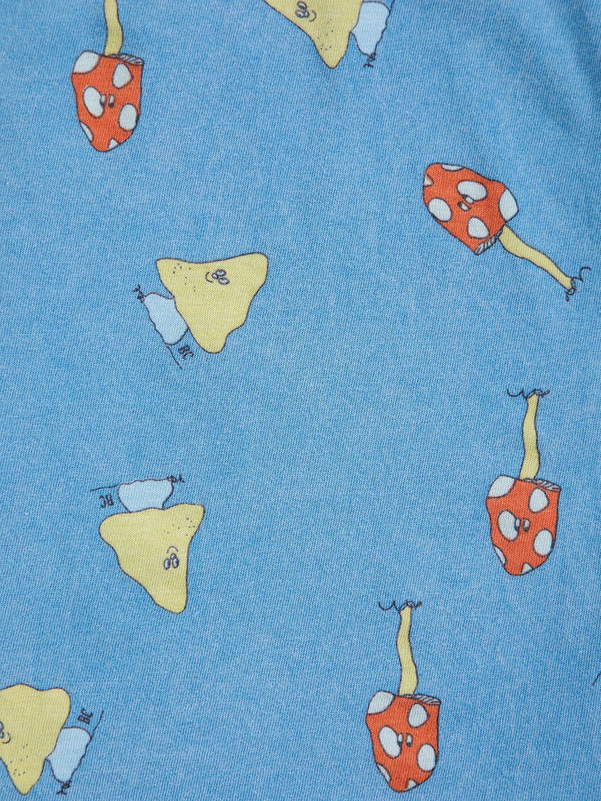 A close-up of a blue fabric surface printed with whimsical mushroom motifs in red, yellow, and light blue.