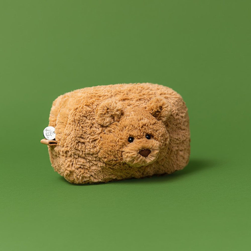 Plush bear-shaped pillow on a green background