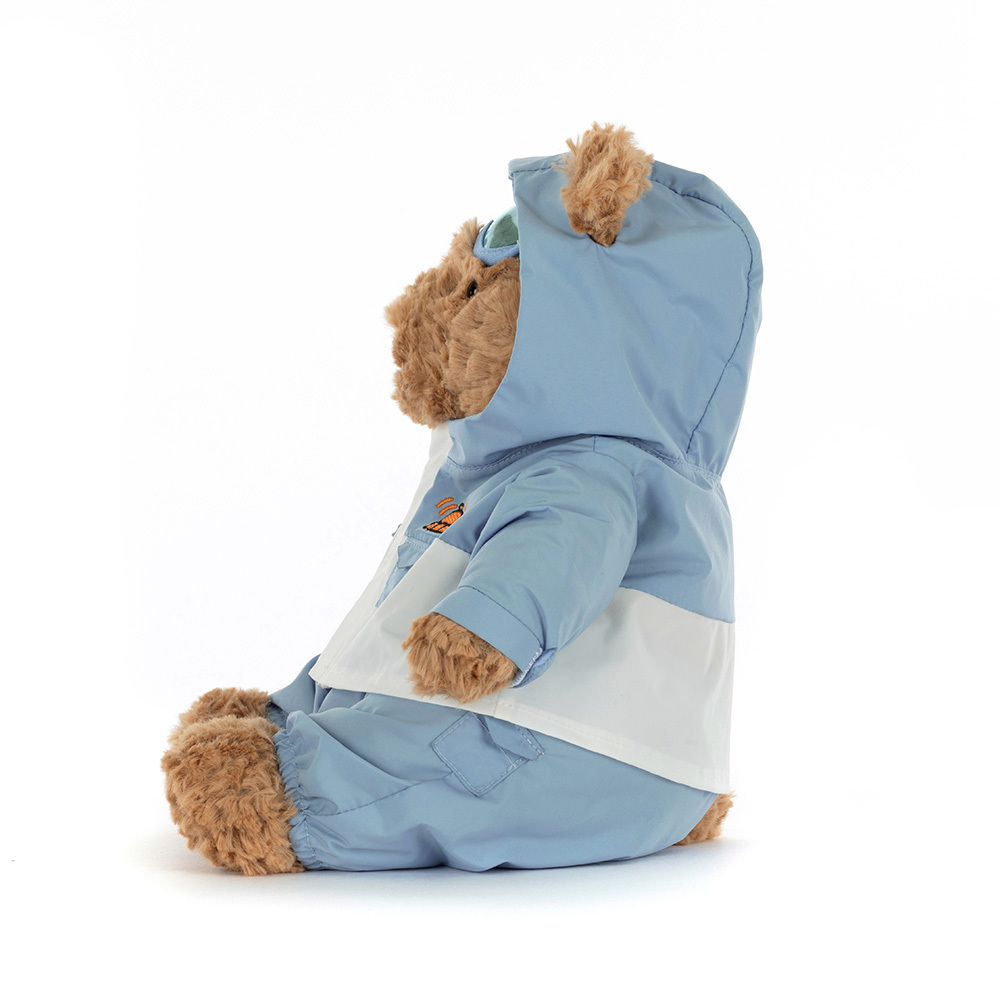 Stuffed teddy bear wearing a blue raincoat on a white background