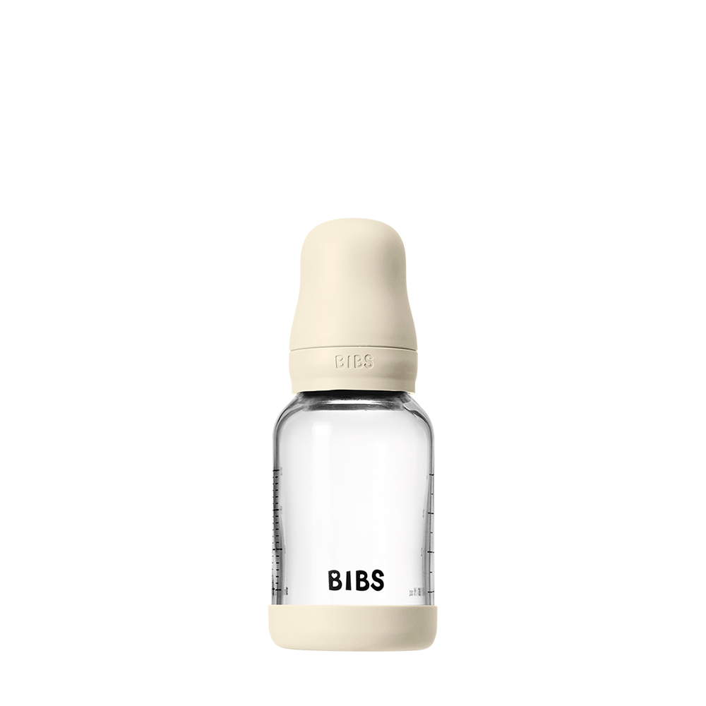Clear glass baby bottle with beige cap and 'BIBS' branding on a white background