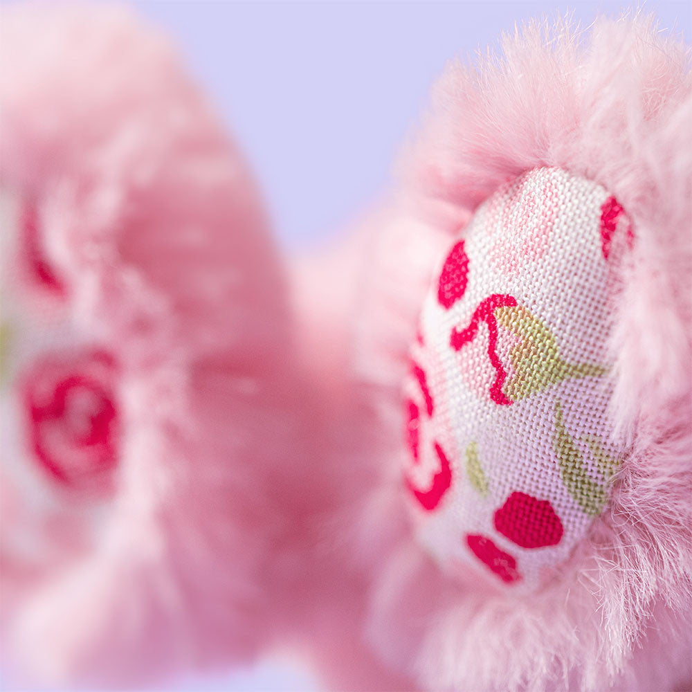 Close-up of pink baby booties with floral pattern on a blurred background