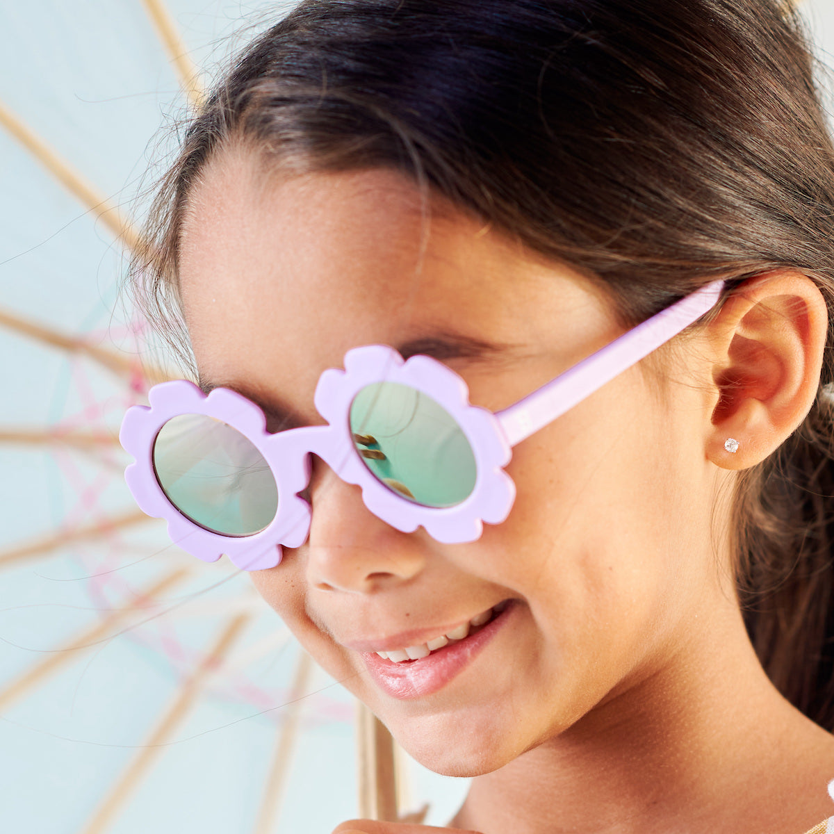 Close-up of a child wearing pink flower-shaped sunglasses with a blurred background