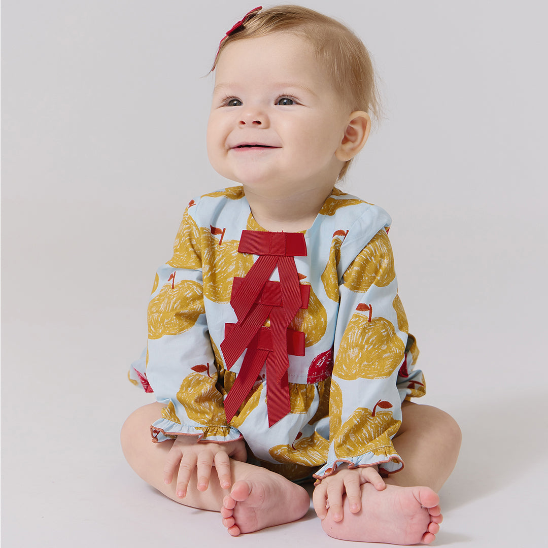 Baby wearing a colorful outfit with a red letter 'A' on a light background