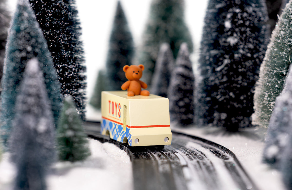 Teddy bear on a toy train in a snowy forest setting